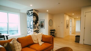 A modern living room with a sofa, a coffee table, and a large abstract wall art piece. - Chic Cozy Retreat - 2BR - Stunning North End Views (Halifax)