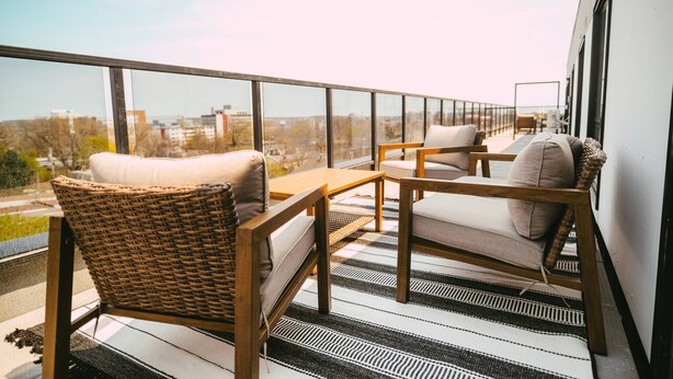 A balcony with wicker furniture, a striped rug, and a city view. - Chic Cozy Retreat - 2BR - Stunning North End Views (Halifax)