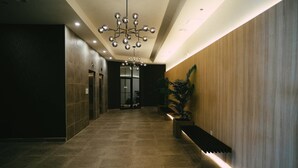 A modern hotel lobby with a long corridor, a central chandelier, and a wooden accent wall. - Chic Cozy Retreat - 2BR - Stunning North End Views (Halifax)