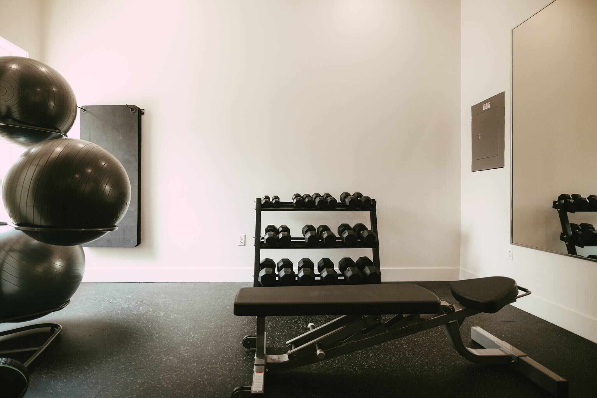 A gym with exercise equipment, a bench, and a rack of dumbbells.
