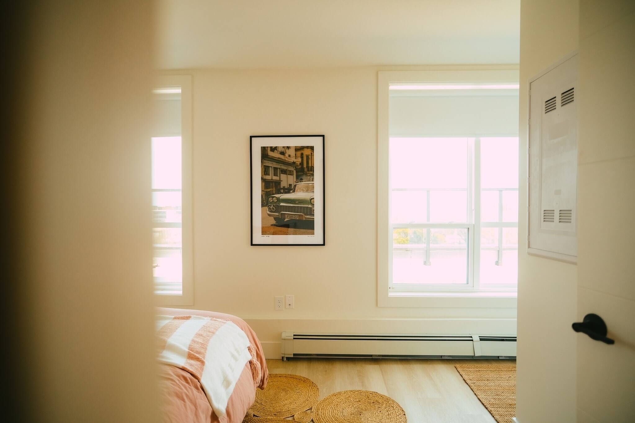 Une chambre à coucher avec un lit, un radiateur, une fenêtre et un tableau encadré accroché au mur.