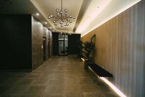 A modern hotel lobby with a long corridor, a central chandelier, and a wooden accent wall. - Chic Cozy Retreat - 2BR - Stunning North End Views (Halifax)