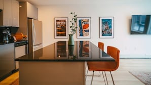 A modern kitchen with a black countertop, stainless steel appliances, and framed artwork on the wall. - Chic Cozy Retreat - 2BR - Stunning North End Views (Halifax)