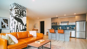 A modern living room with a sofa, coffee table, and a kitchen with bar stools. - Chic Cozy Retreat - 2BR - Stunning North End Views (Halifax)