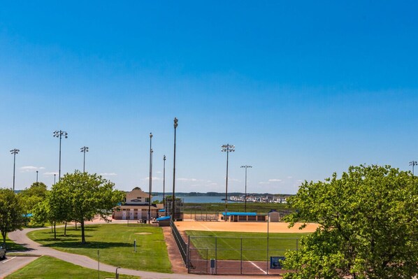 A baseball field with a clear sky, trees, and a distant view of a body of water.