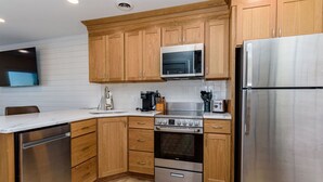 A modern kitchen with wooden cabinets, stainless steel appliances, a microwave, and a built-in oven. - North OC-short walk 2 beach & Park (Ocean City)