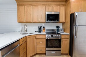 A modern kitchen with wooden cabinets, stainless steel appliances, a microwave, oven, and a dishwasher.