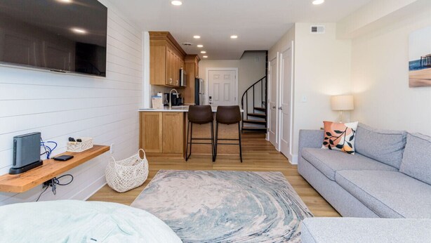 A compact living space with a kitchenette, a sofa, a TV, and a staircase leading to another level. - North OC-short walk 2 beach & Park (Ocean City)