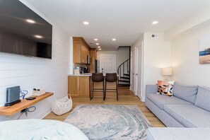 A compact living space with a kitchenette, a sofa, a TV, and a staircase leading to another level.