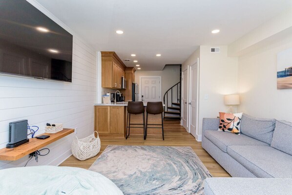 A compact living space with a kitchenette, a sofa, a TV, and a staircase leading to another level.