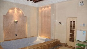 Un'area benessere con una vasca da bagno ampia, una porta in legno e un piccolo tavolo con un tappetino verde.