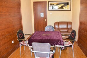 A room with a wooden door, a framed picture on the wall, a table with a purple tablecloth, and four chairs. - Yunnan Cadre Sanatorium (Anning)