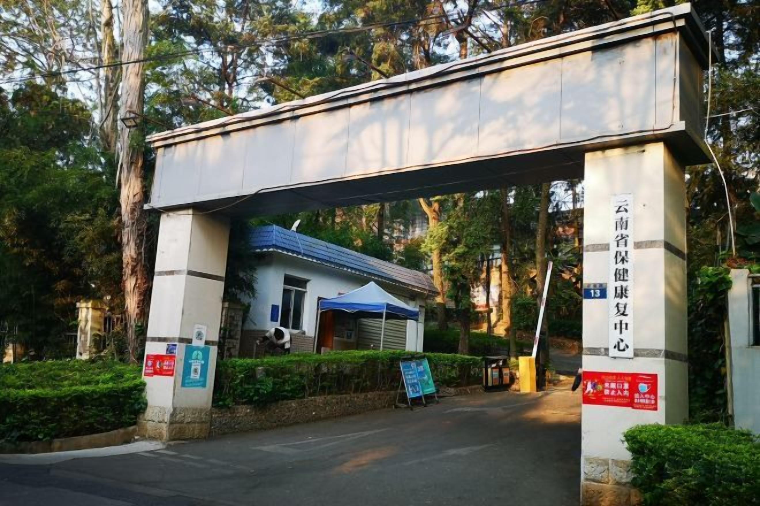 A covered entrance to a building with signage in a foreign language, a blue awning, and a sign indicating a parking area.