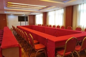 A conference room with a long table and chairs, a flat-screen TV, and a window with curtains. - Yunnan Cadre Sanatorium (Anning)