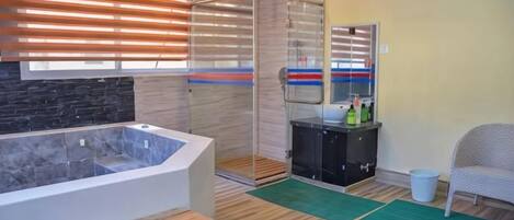 A bathroom with a bathtub, shower, and a vanity with toiletries.