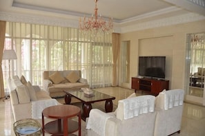 Amplia sala de estar con sofá, mesa de centro, televisor y candelabro.