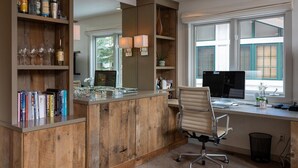 Un bureau à domicile avec un bureau en bois, un ordinateur et des étagères remplies de livres et de bouteilles.