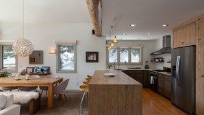 Une cuisine moderne avec des meubles en bois, un îlot central et un réfrigérateur en acier inoxydable.