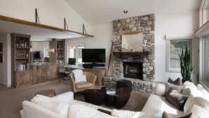 Un salon moderne avec une cheminée en pierre, un téléviseur et un coin salon confortable.