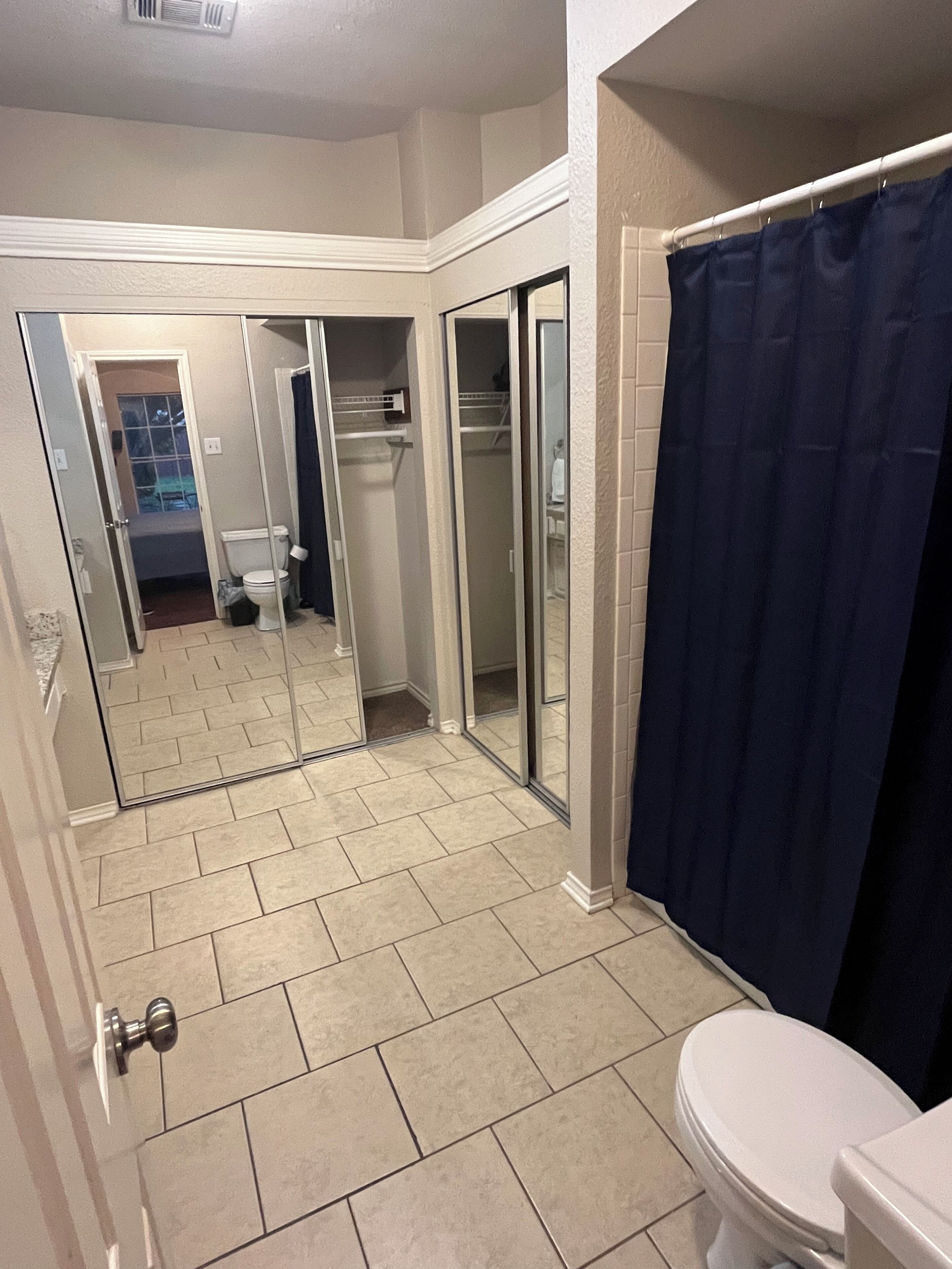 Un baño con inodoro, cortina de ducha y cabina de ducha con mampara de vidrio.
