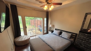 Une chambre à coucher avec un lit, un ventilateur de plafond, une fenêtre et une vue sur l’extérieur.