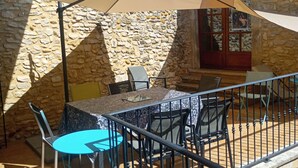 An outdoor patio area with stone walls, a table with chairs, and a covered seating area. - Proche Avignon Grande Maison calme en pierres avec cour intérieure,10 personnes (Saint Laurent des Arbres)