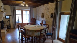 A dining area with a round table, wooden chairs, and a stone wall. - Proche Avignon Grande Maison calme en pierres avec cour intérieure,10 personnes (Saint Laurent des Arbres)