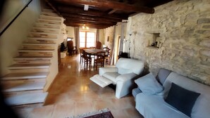A spacious living area with a stone wall, a staircase, a dining area, and a sofa. - Proche Avignon Grande Maison calme en pierres avec cour intérieure,10 personnes (Saint Laurent des Arbres)