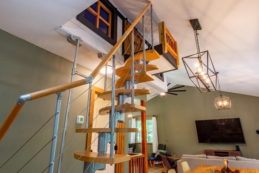 Un interior moderno con una escalera en espiral, un televisor de pantalla plana y un comedor.