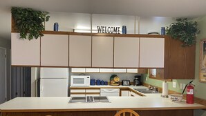 A kitchen with a central island, wooden cabinets, a microwave, a toaster, and a coffee maker. - Port Angeles History House (Port Angeles)