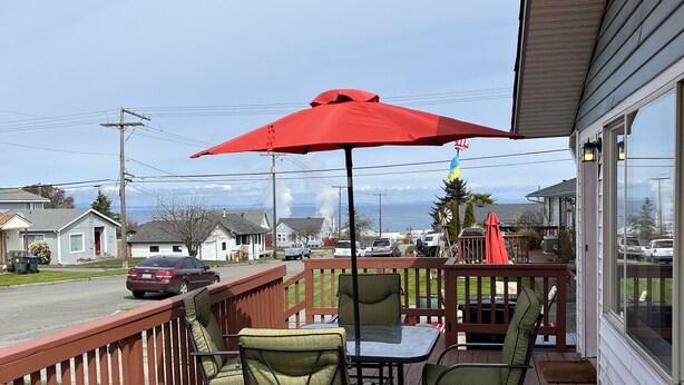 A wooden deck with outdoor furniture and a red umbrella. - Port Angeles History House (Port Angeles)