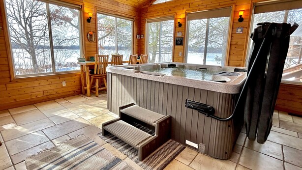 A wooden cabin interior with a hot tub, wooden flooring, and large windows. - Stunning Lakehouse with hot tub & tree house (Richfield Township)