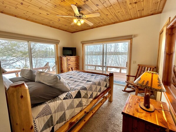 A bedroom with a bed, a wooden dresser, a television, and a lamp.