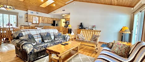 Un vaste salon doté d’un plafond en bois, d’un ensemble de canapés, d’une table basse et d’un coin repas avec des meubles en bois.