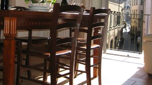 Zona pranzo con tavolo apparecchiato per due, una bottiglia di vino e vista su un edificio storico attraverso una finestra.