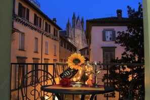 A balcony with a table set for two, featuring a bottle, glasses, a rose, and a candle. - The little terrace on the cathedral (Orvieto)