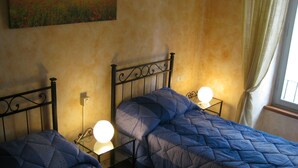 Una stanza con due letti singoli, ognuno dotato di testiera e comodino con lampada.