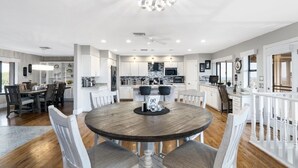 A spacious kitchen with white cabinets, a central island, and a dining area with a round table and chairs.