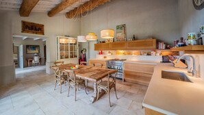 Une cuisine spacieuse avec une table et des chaises en bois, un four encastré et des luminaires suspendus.