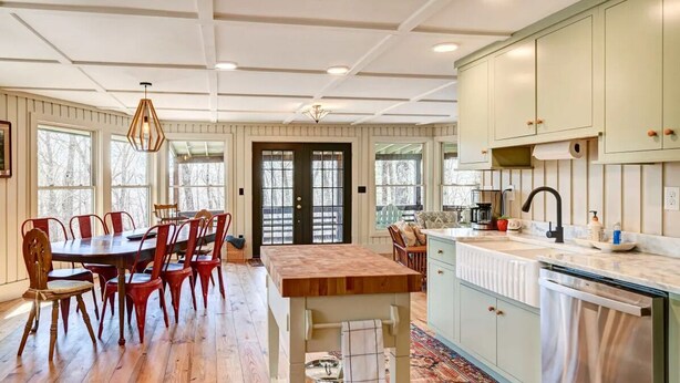 A kitchen with wooden cabinets, a dining table with chairs, and a large window. - Beautiful Highlands Cabin: Large Game Room, Hot Tub (Highlands)