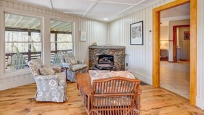 A cozy room with a stone fireplace, wooden furniture, and large windows. - Beautiful Highlands Cabin: Large Game Room, Hot Tub (Highlands)