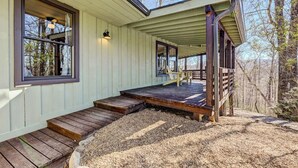 A cabin with a covered porch, wooden steps, and a view of trees. - Beautiful Highlands Cabin: Large Game Room, Hot Tub (Highlands)