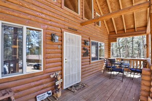 A log cabin with a porch, a welcome sign, and a wooden bench. - Cozy Wooded Log Cabin | Hot Tub | Wood Stove | Games (Florissant)