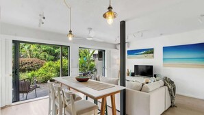 A modern living room with a dining area, a sofa, and a TV.