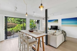 A modern living room with a dining area, a sofa, and a TV.