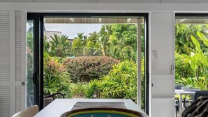 A modern interior with a dining area, a view of a lush garden through glass doors, and a patterned bowl on the table.