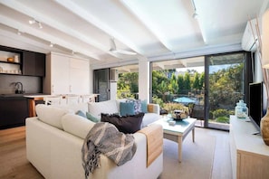 A modern living room with a sofa, coffee table, and a view of the outdoors.