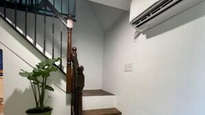 A staircase with wooden steps and a metal railing, a potted plant, and an air conditioning unit on the wall. - Tree Top Oasis Near Waco (Mart)