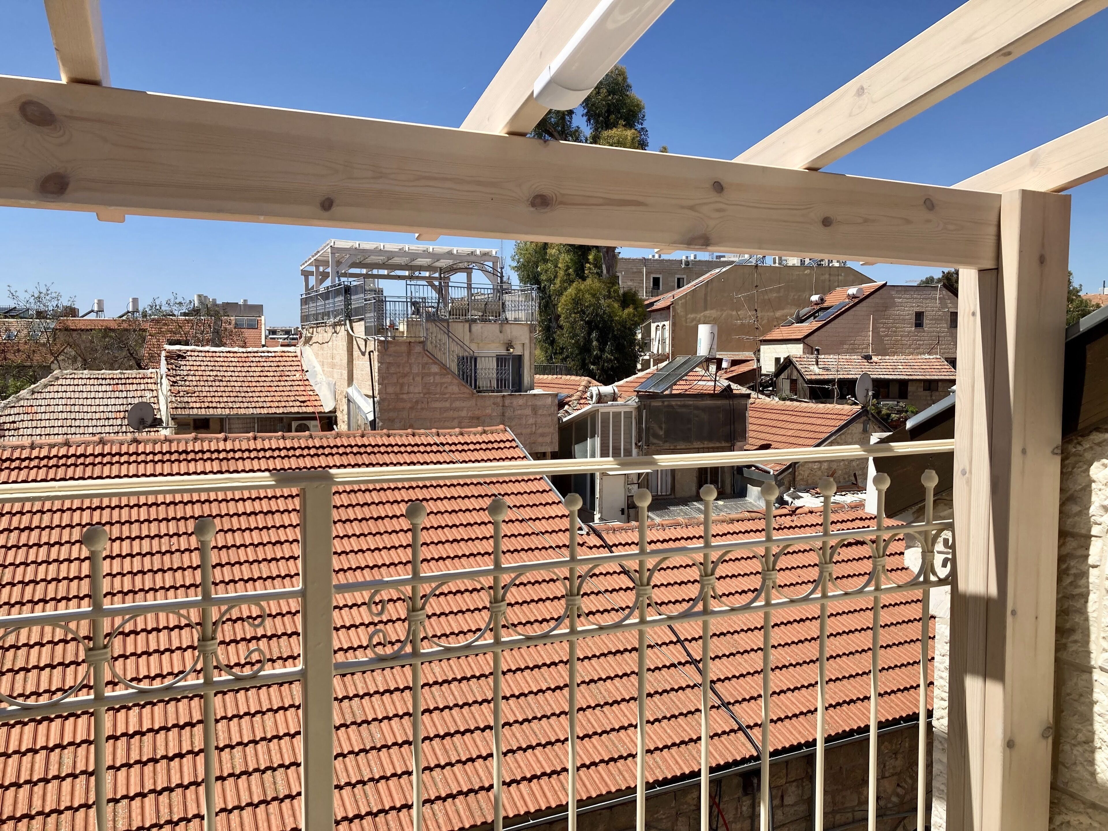 Vue sur des toits recouverts de tuiles en terre cuite et sur un bâtiment en construction.