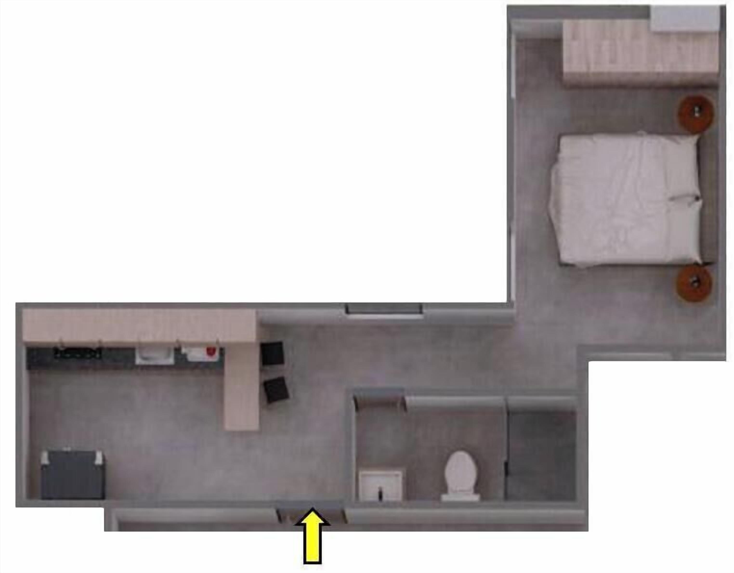A hotel room layout with a bed, a small desk, a chair, a toilet, and a wardrobe.